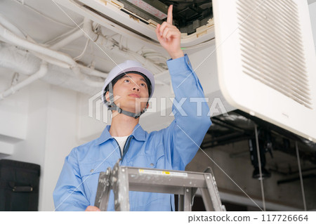 A worker inspecting an air conditioning system A worker inspecting an air conditioning system 117726664