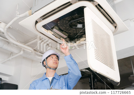 A worker inspecting an air conditioning system A worker inspecting an air conditioning system 117726665