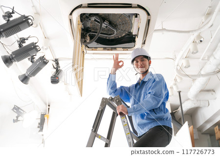 A worker inspecting an air conditioning system 117726773