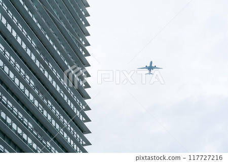 An airplane flying over a building 117727216