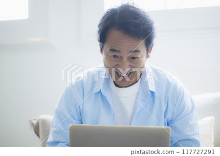 中年男子在客廳使用筆記型電腦 117727291