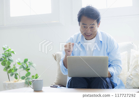 Middle-aged man using a laptop in the living room 117727292