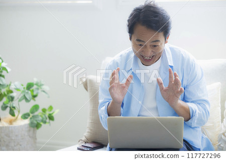 Middle-aged man using a laptop in the living room 117727296
