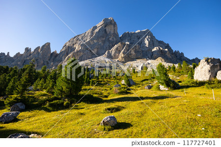 Mountain peak of Mont-de-Fornel, Dolomites stands majestically between sky and hilly valley Mountain peak of Mont-de-Fornel, Dolomites stands majestically between sky and hilly valley 117727401