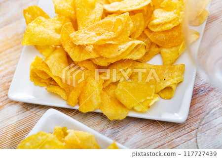 Crispy salty potato chips with natural taste on plate Crispy salty potato chips with natural taste on plate 117727439