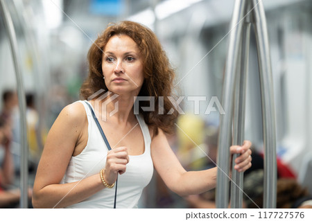 Adult woman stands in subway car 117727576