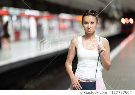 Adult woman stands at subway station 117727604