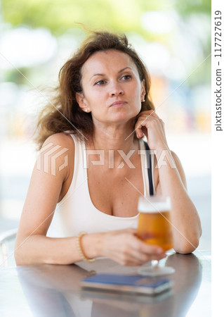 Adult woman drinking beer on cafe terrace 117727619