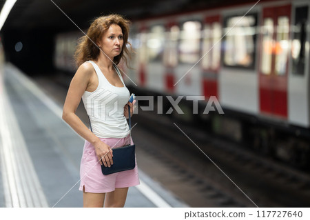 Woman waiting for subway train at an underground station 117727640