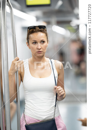 Adult woman stands in subway car Adult woman stands in subway car 117727720