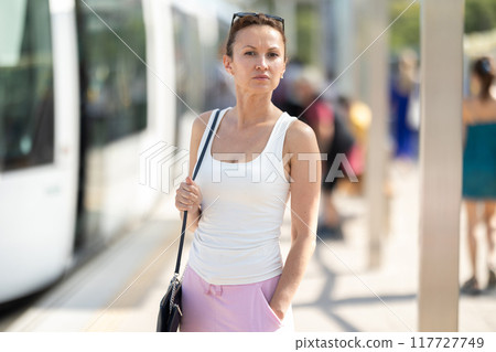Adult woman standing at train station Adult woman standing at train station 117727749