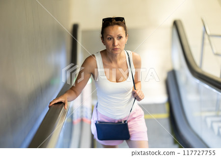 Adult woman standing on escalator in subway 117727755