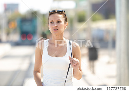 Adult woman standing at train station 117727768