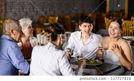 Elderly couple and young couple and adult woman having dinner in restaurant 117727818