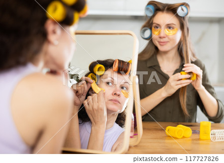 Two women curl their hair with curlers and use patches Two women curl their hair with curlers and use patches 117727826