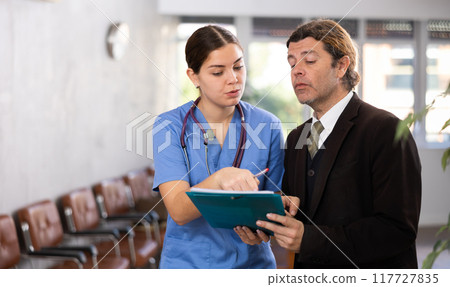 Adult man in suit and young woman doctor with folder of documents 117727835