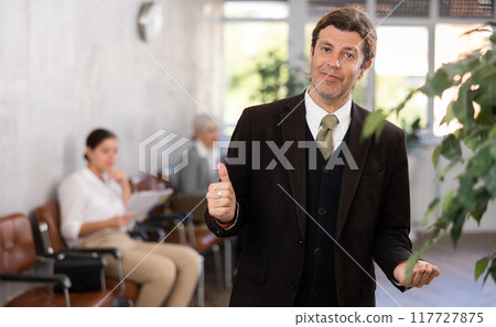 Interested adult businessman in formal suit inviting to office Interested adult businessman in formal suit inviting to office 117727875