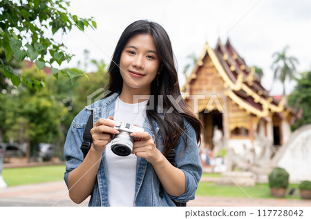An attractive Asian female traveller is smiling at the camera, visiting Thai temple in Chiang mai. 117728042