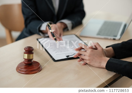 Two people are sitting at a table with a pen and a piece of paper Two people are sitting at a table with a pen and a piece of paper 117728653