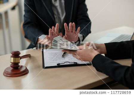 Two people are sitting at a desk with a judge's gavel on the table Two people are sitting at a desk with a judge's gavel on the table 117728659