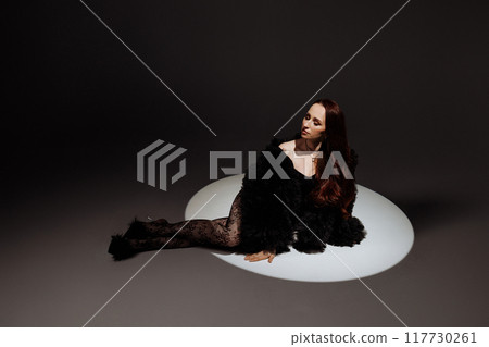 A woman in a black dress is laying on the ground A woman in a black dress is laying on the ground 117730261