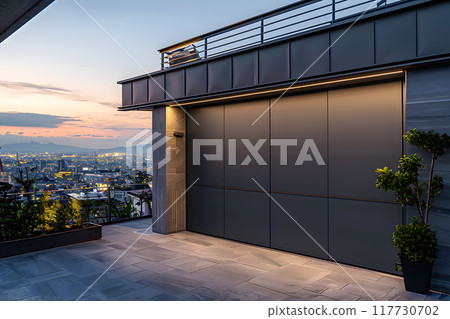 A composite material garage door is fixed to the buildings facade, blending into the landscape under the cloudy sky, providing shade for parked vehicles A composite material garage door is fixed to the buildings facade, blending into the landscape under the cloudy sky, providing shade for parked vehicles 117730702