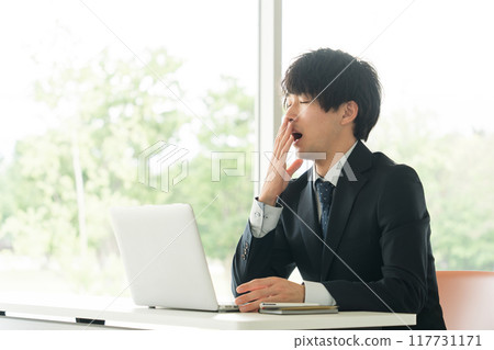 Young businessman yawning Young businessman yawning 117731171