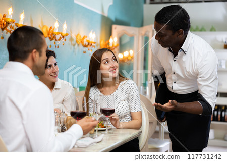 Waiter serving two women at the restaurant Waiter serving two women at the restaurant 117731242