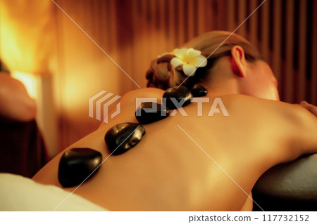 Hot stone massage at spa salon in luxury resort with warm candle light.Quiescent 117732152