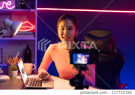 Smiling Asian influencer recording on camera with positive. Stratagem. Smiling Asian influencer recording on camera with positive. Stratagem. 117732166