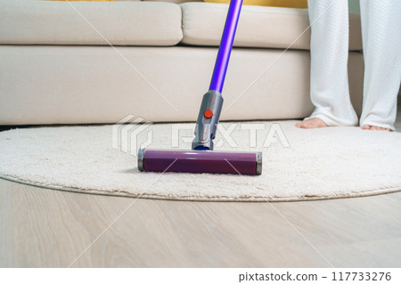 Woman cleaning Carpet with cordless Vacuum cleaner. Housewife using wireless Vacuum for big cleaning home. Housework, Housecleaning, Housekeeping, Removes dust, Domestic hygiene and daily routine Woman cleaning Carpet with cordless Vacuum cleaner. Housewife using wireless Vacuum for big cleaning home. Housework, Housecleaning, Housekeeping, Removes dust, Domestic hygiene and daily routine 117733276