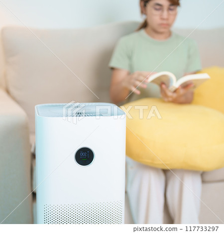 Air Purifier with woman read and relax on sofa. Purification system for filter and cleaning dust PM2.5 HEPA and virus in home. Allergy, Pure air, health lifestyle, Wellness life and Air Pollution Air Purifier with woman read and relax on sofa. Purification system for filter and cleaning dust PM2.5 HEPA and virus in home. Allergy, Pure air, health lifestyle, Wellness life and Air Pollution 117733297