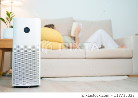 Air Purifier with woman read and relax on sofa. Purification system for filter and cleaning dust PM2.5 HEPA and virus in home. Allergy, Pure air, health lifestyle, Wellness life and Air Pollution Air Purifier with woman read and relax on sofa. Purification system for filter and cleaning dust PM2.5 HEPA and virus in home. Allergy, Pure air, health lifestyle, Wellness life and Air Pollution 117733322