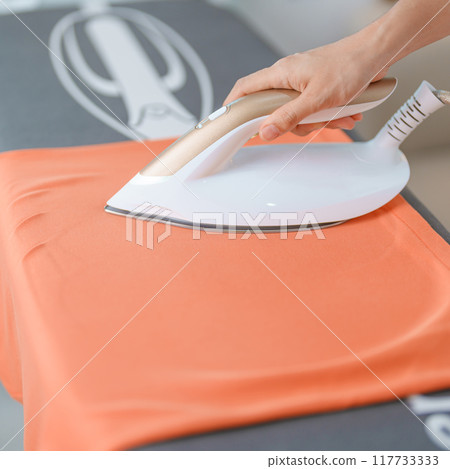 Woman hold Electric hot iron press T shirt clothes on ironing board, Intelligent automatic steam iron. Laundry, Housework, Housekeeping, Domestic hygiene, household of chores and daily routine concept Woman hold Electric hot iron press T shirt clothes on ironing board, Intelligent automatic steam iron. Laundry, Housework, Housekeeping, Domestic hygiene, household of chores and daily routine concept 117733333