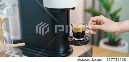 hand making Espresso Coffee by Coffee Maker Machine with Capsule of roasted coffee bean on wood table bar. Daily beverage drink at Home, Apartment and Office concept hand making Espresso Coffee by Coffee Maker Machine with Capsule of roasted coffee bean on wood table bar. Daily beverage drink at Home, Apartment and Office concept 117733368