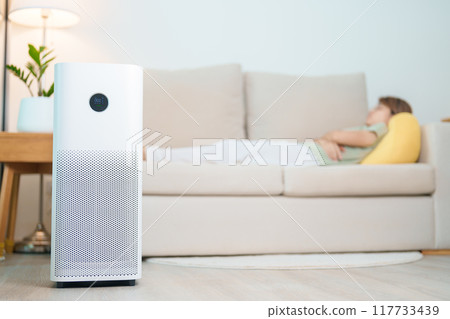 Air Purifier with woman relax and sleep on sofa. Purification system for filter and cleaning dust PM2.5 HEPA and virus in home. Allergy, Pure air, health, Wellness lifestyle and Air Pollution 117733439