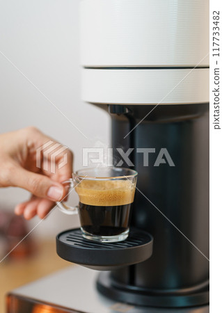 hand making Espresso Coffee by Coffee Maker Machine with Capsule of roasted coffee bean on wood table bar. Daily beverage drink at Home, Apartment and Office concept hand making Espresso Coffee by Coffee Maker Machine with Capsule of roasted coffee bean on wood table bar. Daily beverage drink at Home, Apartment and Office concept 117733482