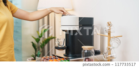 hand making Espresso Coffee by Coffee Maker Machine with Capsule of roasted coffee bean on wood table bar. Daily beverage drink at Home, Apartment and Office concept hand making Espresso Coffee by Coffee Maker Machine with Capsule of roasted coffee bean on wood table bar. Daily beverage drink at Home, Apartment and Office concept 117733517