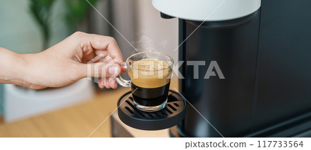 Espresso cup with steam and froth during Coffee making Coffee by Coffee Maker Machine on wood table bar. Cafe shop, Daily beverage drink at Home, Apartment and Office concept Espresso cup with steam and froth during Coffee making Coffee by Coffee Maker Machine on wood table bar. Cafe shop, Daily beverage drink at Home, Apartment and Office concept 117733564