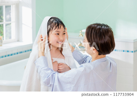 A mother wipes her daughter with a towel after a bath 117733904
