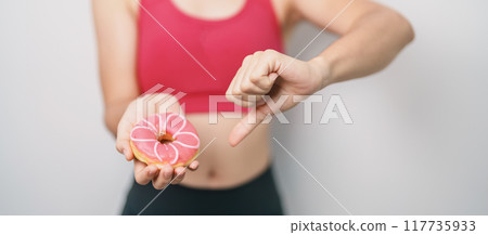 woman hand hold Donut with tape measure, choose stop eating sweet is Unhealthy ealthy food. Dieting control, Weight loss, Obesity, eating lifestyle and nutrition concepts woman hand hold Donut with tape measure, choose stop eating sweet is Unhealthy ealthy food. Dieting control, Weight loss, Obesity, eating lifestyle and nutrition concepts 117735933