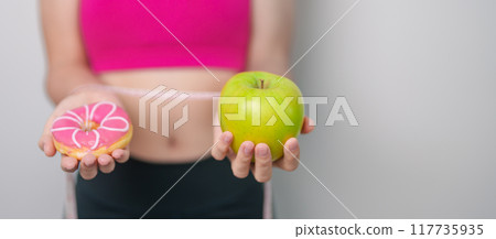 woman hand hold green Apple and donut, female fitness choose between fruit is Healthy and sweet is Unhealthy junk food. Dieting control, Weight loss, Obesity, eating lifestyle and nutrition concept woman hand hold green Apple and donut, female fitness choose between fruit is Healthy and sweet is Unhealthy junk food. Dieting control, Weight loss, Obesity, eating lifestyle and nutrition concept 117735935