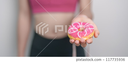 woman hand hold Donut with tape measure, choose stop eating sweet is Unhealthy ealthy food. Dieting control, Weight loss, Obesity, eating lifestyle and nutrition concepts woman hand hold Donut with tape measure, choose stop eating sweet is Unhealthy ealthy food. Dieting control, Weight loss, Obesity, eating lifestyle and nutrition concepts 117735936