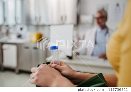 Doctor and tennage girl patient during visit. Girl holding urine test tube. School entry medical exam. 117736221