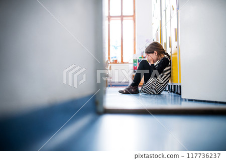 Bullied girl is crying by lockers. Bullying or teasing in elementary school. 117736237