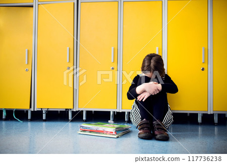 Bullied girl is crying by lockers. Bullying or teasing in elementary school. 117736238