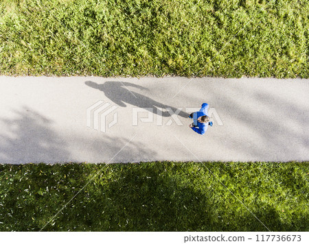 Aerial view of a runner running through autumn park on jogging path. Morning running training. Aerial view of a runner running through autumn park on jogging path. Morning running training. 117736673