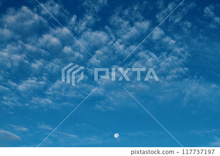 White clouds and a round moon floating in the blue sky White clouds and a round moon floating in the blue sky 117737197