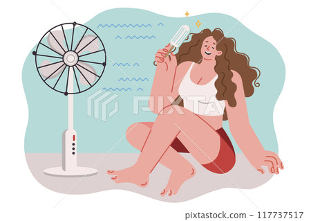 Woman eats ice cream and sits on floor near electric fan, cooling off during warming of summer 117737517