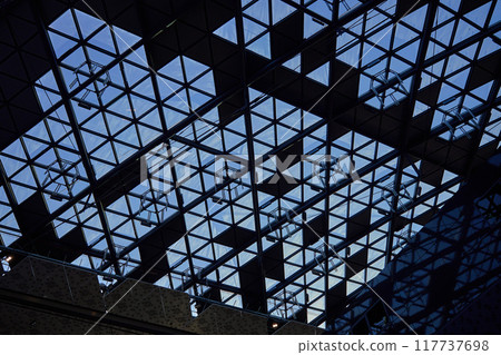 Modern glass ceiling with triangular pattern against blue sky. Contemporary building details. Abstract architecture Modern glass ceiling with triangular pattern against blue sky. Contemporary building details. Abstract architecture 117737698